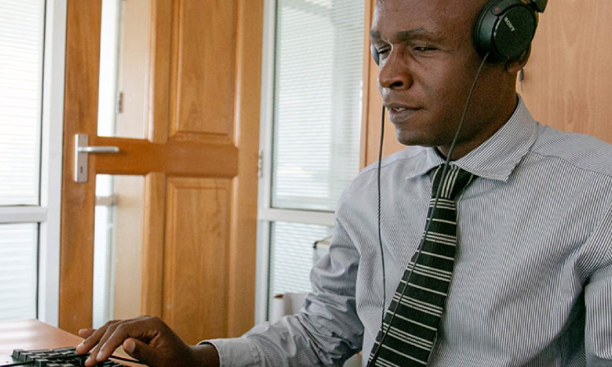 foto de um homem de gravata trabalhando em um computador e usando fones de ouvido. Está escrito: "Direito ao Emprego para as pessoas com deficiência" #direitospcd e há a logo da Retina Brasil