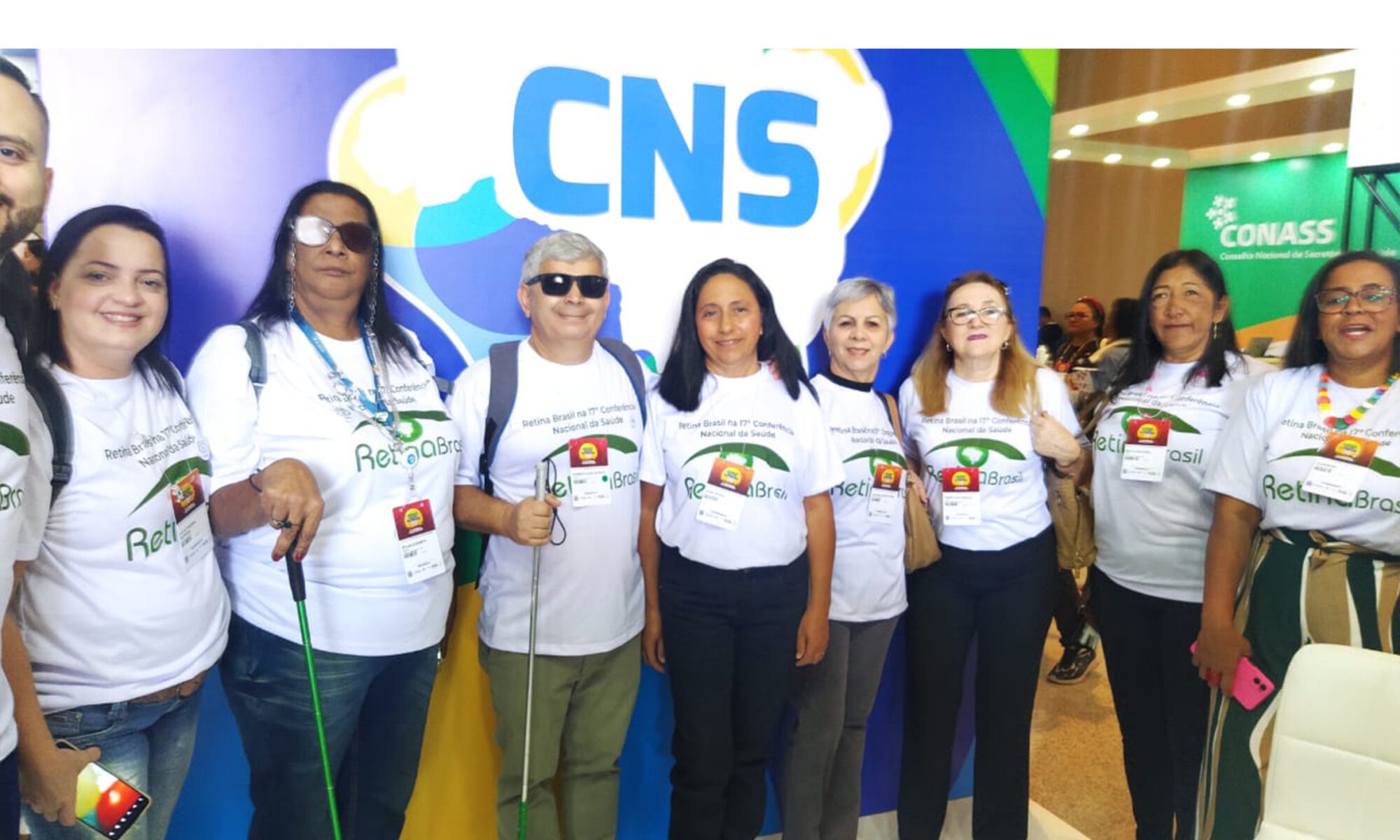 Card Branco com uma foto da delegação da Retina Brasil na 17ª CNS. São 9 pessoas em frente ao painel da CNS. No cabeçalho lê-se: Notícias da Retina Brasil na 17ª CNS e no rodapé o logo da Retina Brasil.